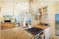 Bright kitchen with gas range, granite countertops, and ocean view