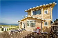 Exterior of the three-level Pelican Point home with a wooden deck, outdoor seating, and barbecue grill.