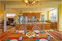 Dining table set for a meal with an open view into the kitchen and living area.