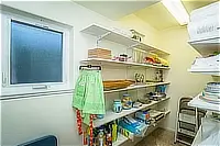 Walk-in pantry with open shelving stocked with dishes, kitchen supplies, and household essentials.