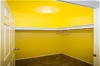 Empty walk-in closet with yellow walls, carpeted floor, and built-in hanging rods and shelves.