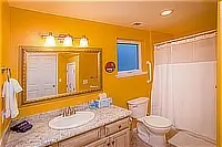 Bathroom with granite vanity, large framed mirror, toilet, and bathtub with shower curtain.