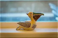 Decorative ceramic pelican figurine resting on a windowsill.